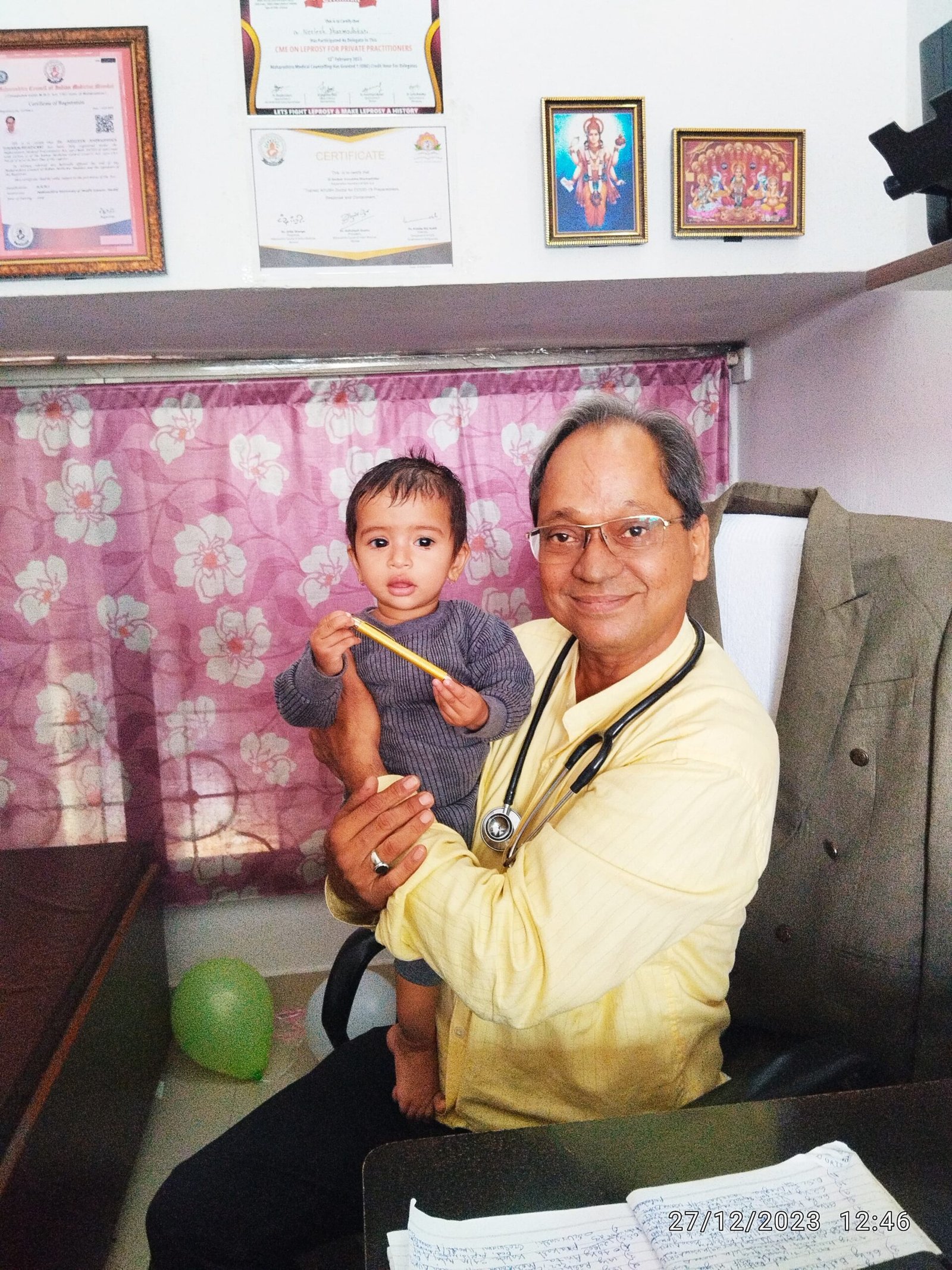 A 2-year-old baby comfortably rests on Dr. N. A. Dharmadhikari’s shoulder during consultation, expressing important health complaints with trust and ease