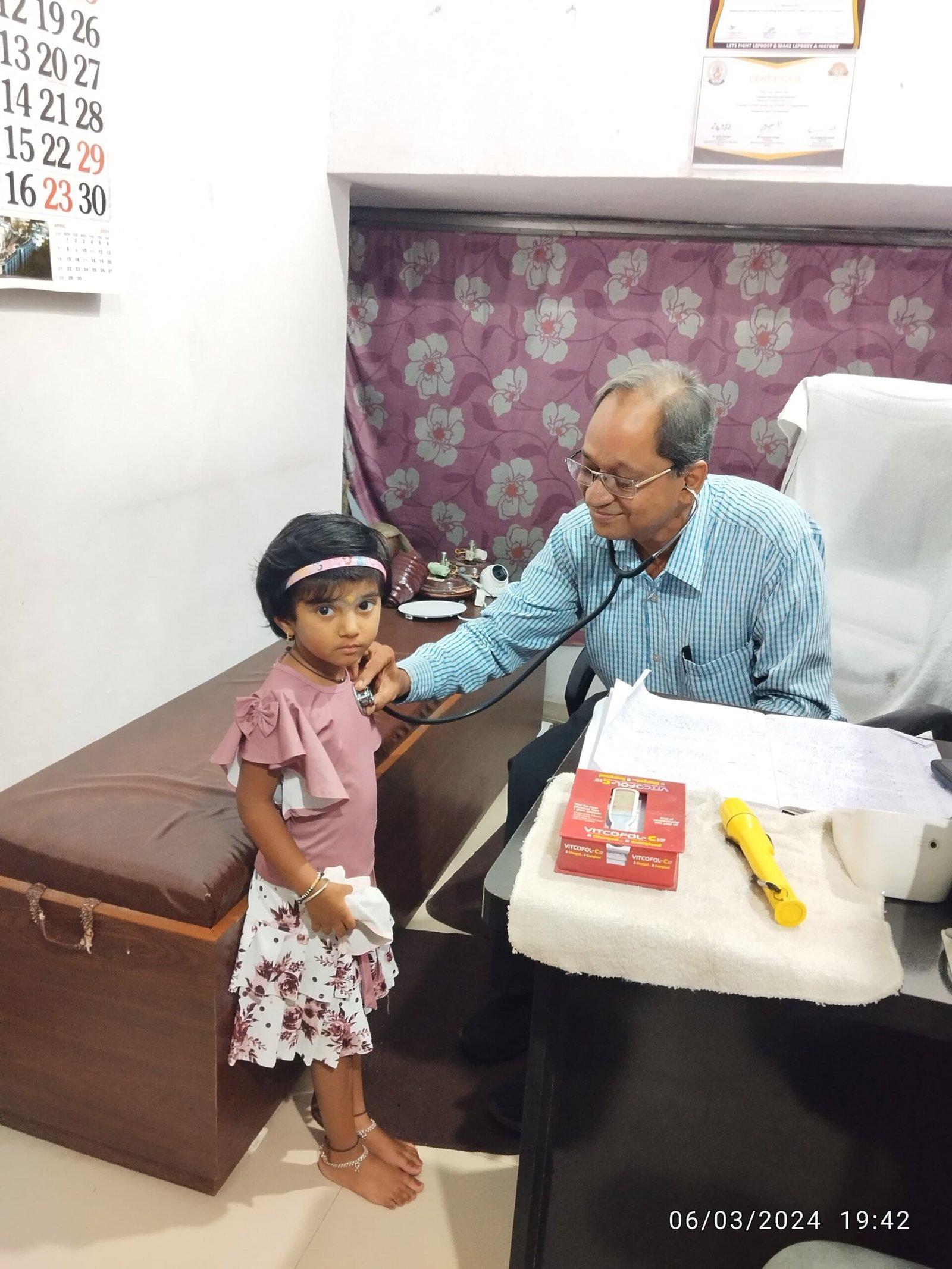 Dr. N. A. Dharmadhikari examining a calm 3-year-old baby with stethoscope, reflecting trust and care